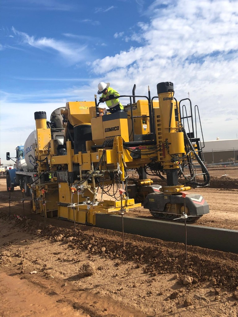 Sandstorm curb and gutter slipform machine placing concrete on site