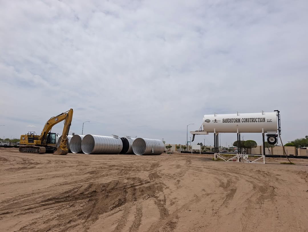 Sandstorm excavator and branded water tower with storm pipe on site